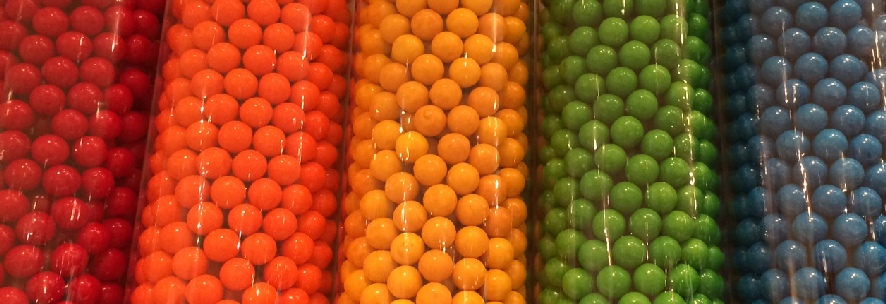 image of gumballs in five tall cylindrical containers, in rainbow order of color